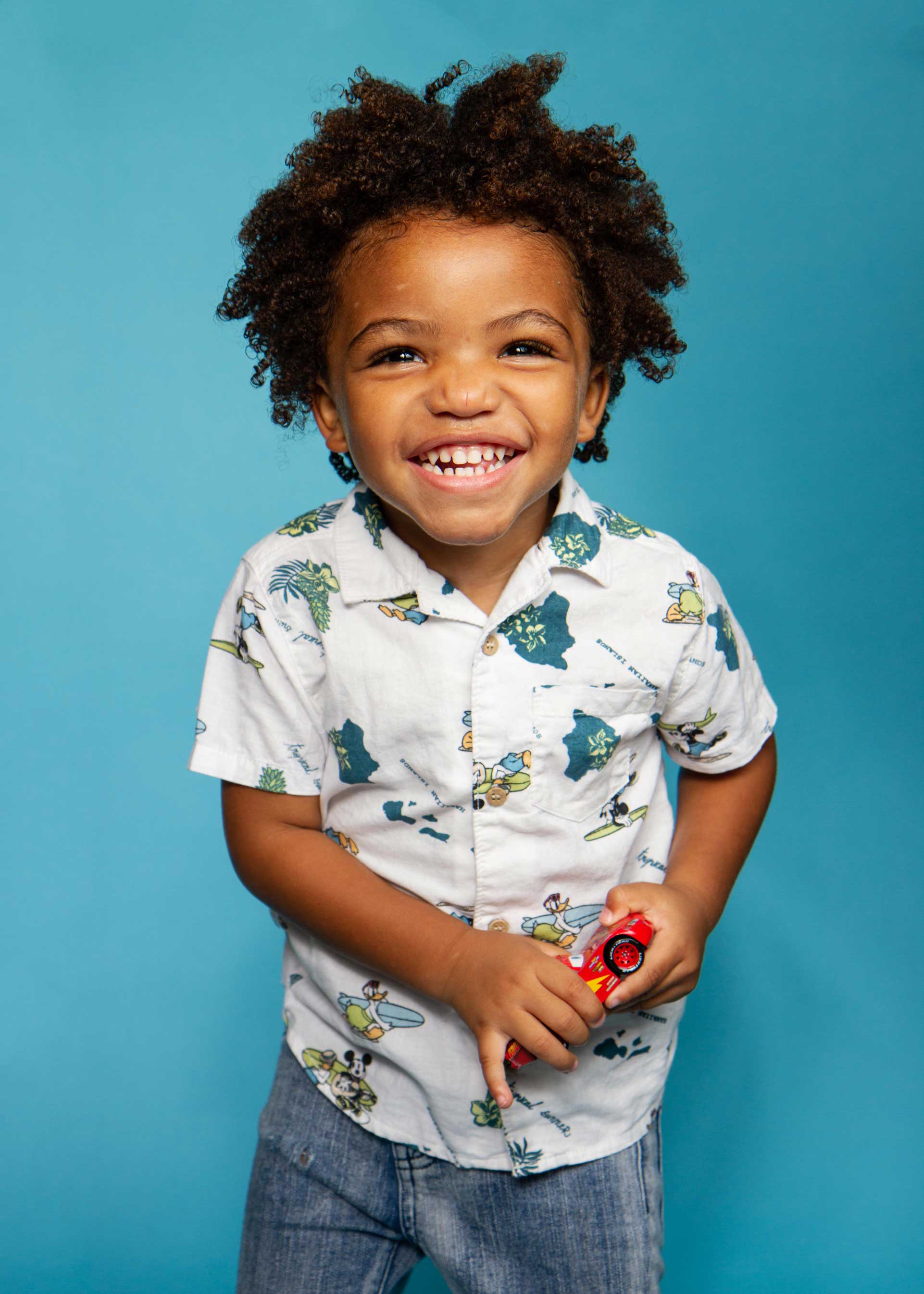 a toddler smiles while holding his toy car