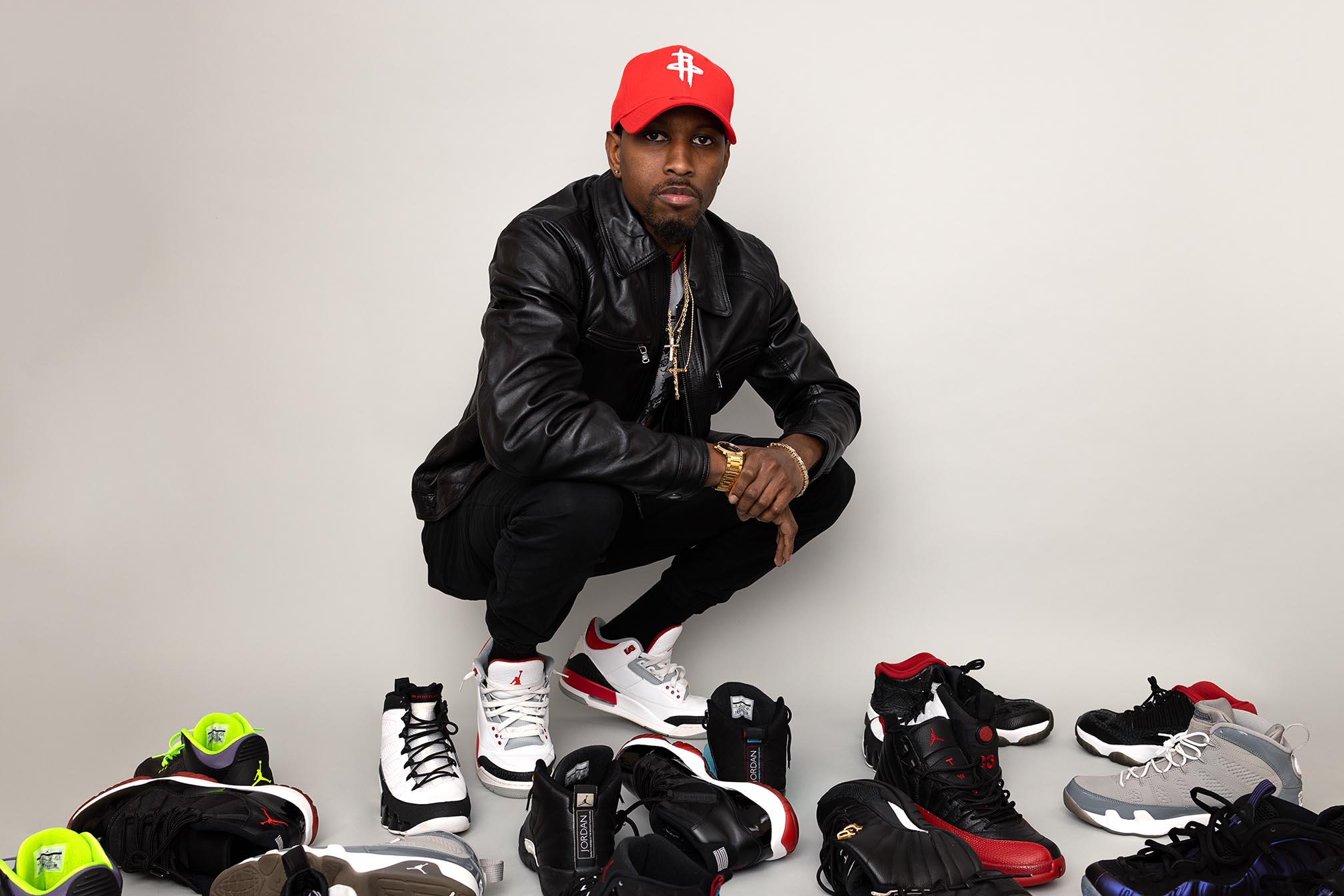 sneaker collector kneels next to his collection of sneakers