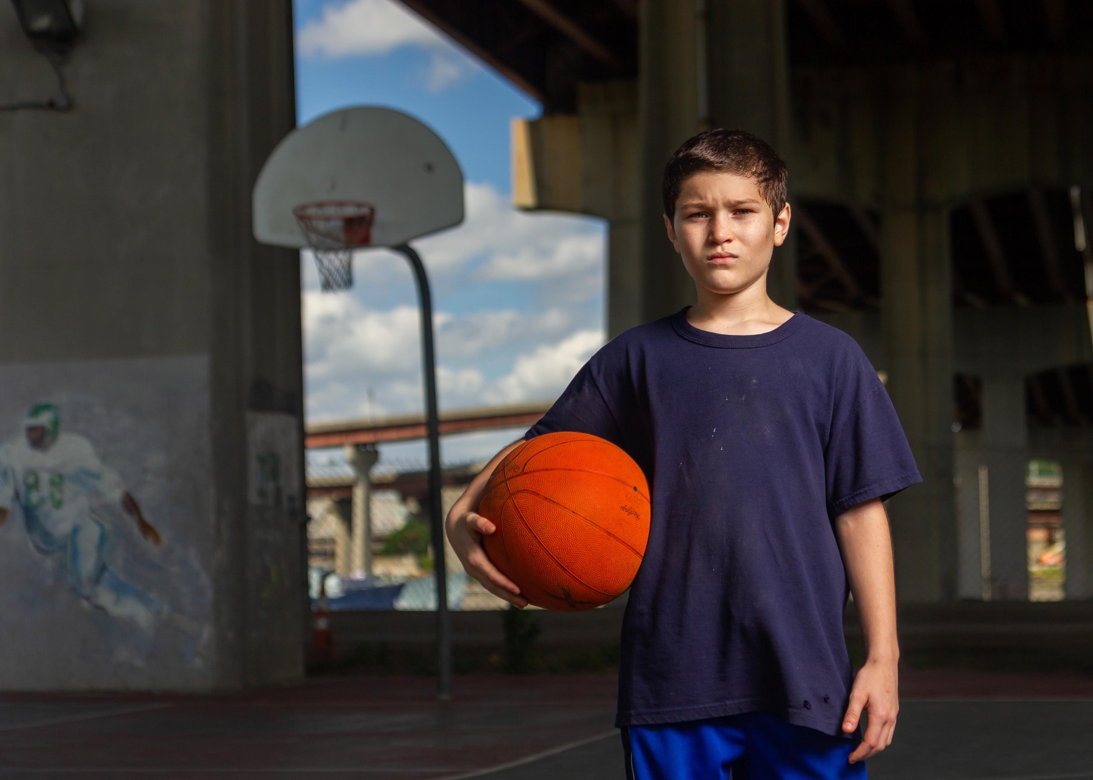 young boy poses on an outdoor basketball court